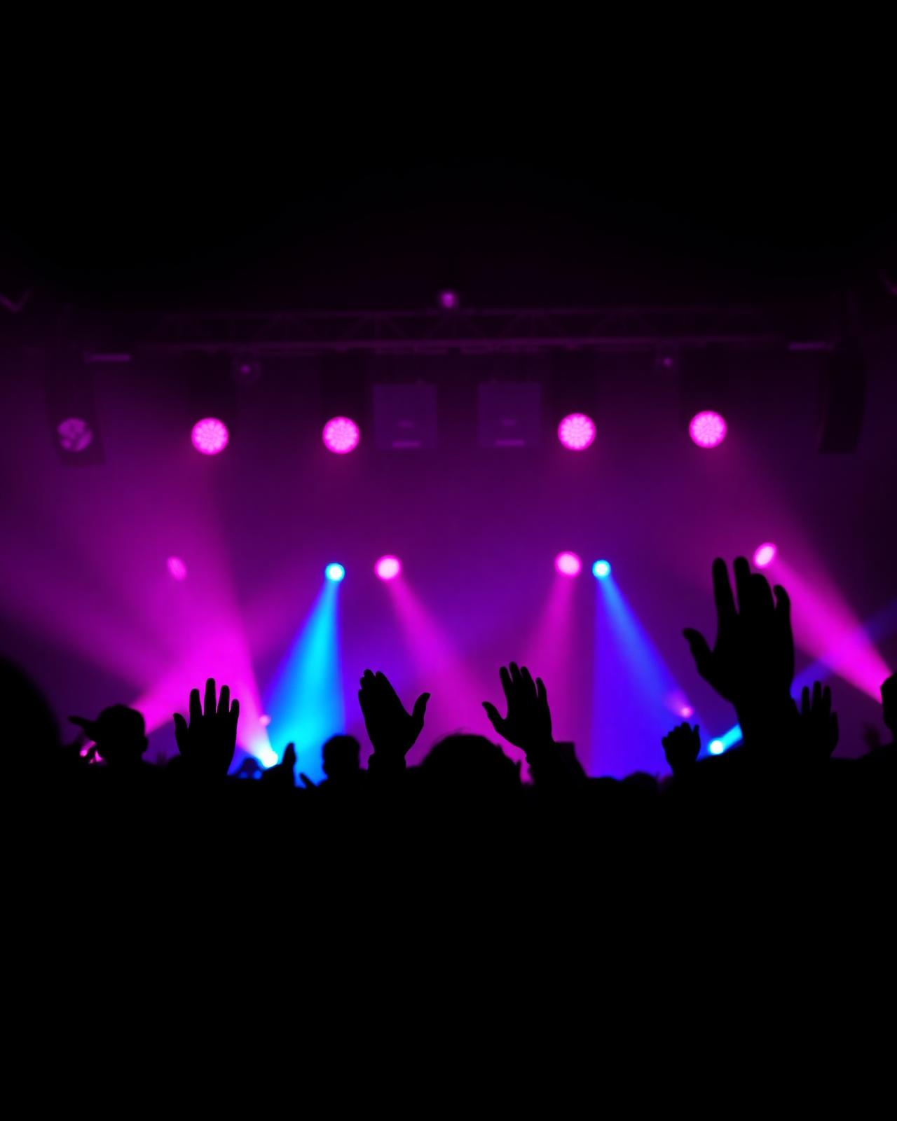 Foule de concert éclairée par des projecteurs magenta et bleus
